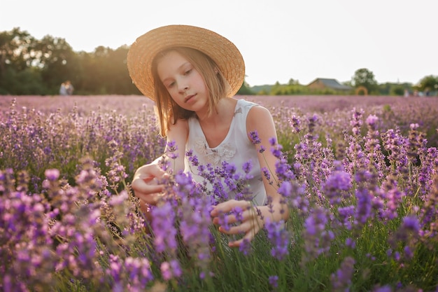 Menina adolescente sonhadora com chapéu de palha sentada no campo de lavanda, beleza da natureza, estilo de vida de verão