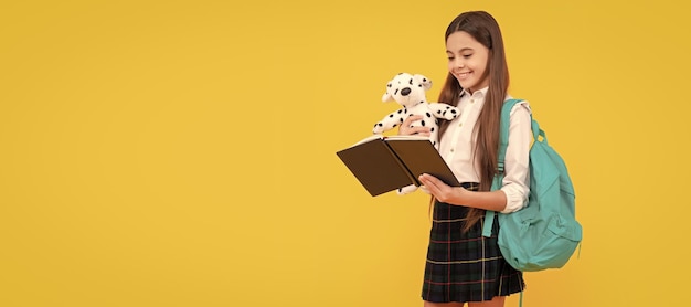 Menina adolescente sorridente com brinquedo de mochila lendo livro em uniforme escolar escola de estudo de corpo inteiro