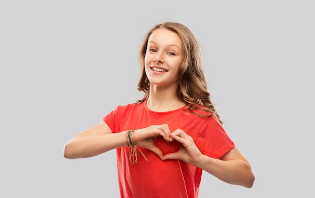 menina adolescente sorridente de vermelho fazendo mão coração