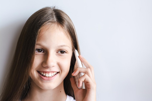 Menina adolescente sorridente falando em um telefone com botão branco