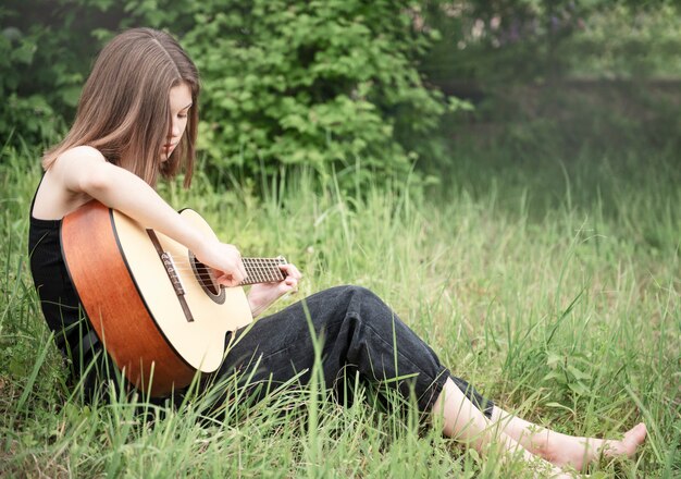 Menina adolescente tocando violão no parque