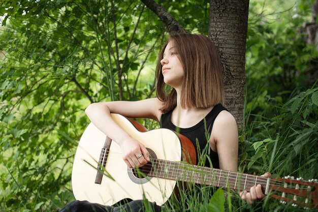 Menina adolescente tocando violão no parque