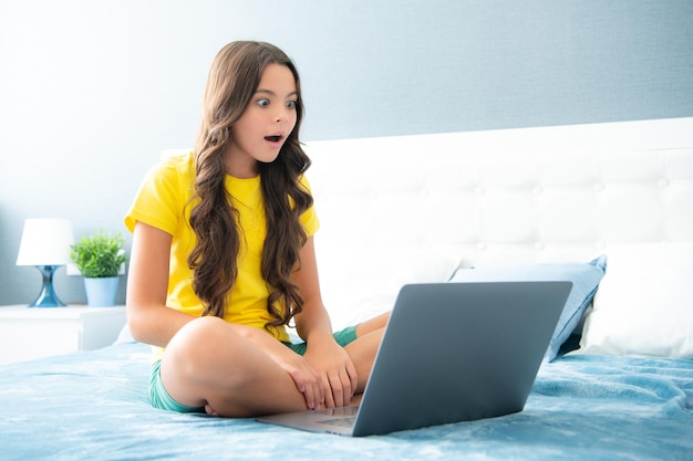 Menina adolescente trabalhando em laptop pc computador deitado na cama descansando relaxante quarto em casa adolescente