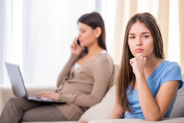 Menina adolescente triste está sentado no sofá