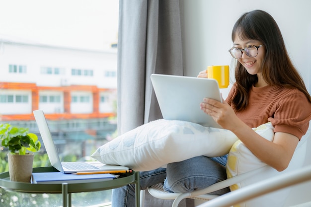 Menina adolescente usando tablet e relaxando na cadeira no café espaço de trabalho.