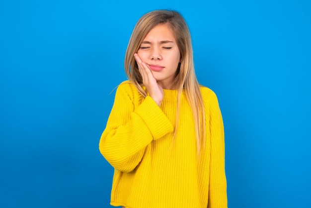 menina adolescente vestindo suéter amarelo com dor de dente