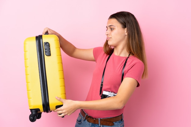 Menina adolescente viajante segurando uma mala isolada rosa com expressão triste