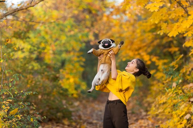 Menina adolescente vomita seu cachorro pug no outono no parque.