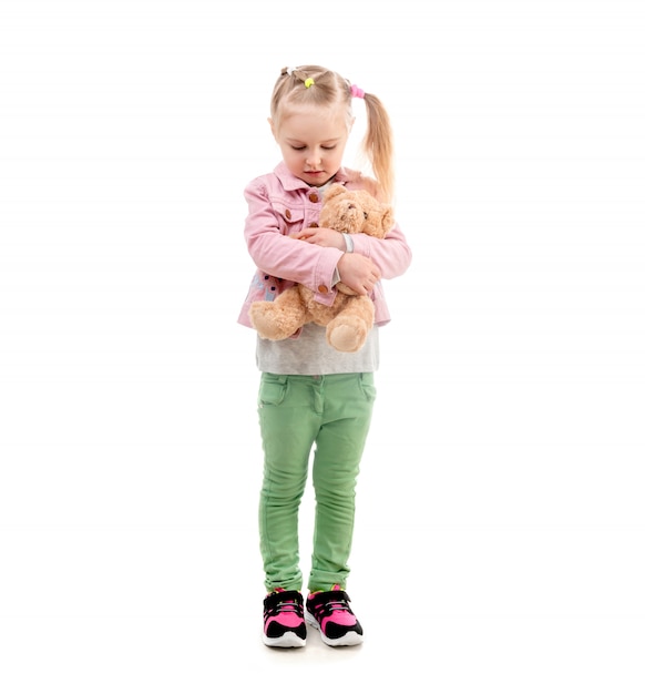 Menina adorável, abraçando o brinquedo, isolado no fundo branco