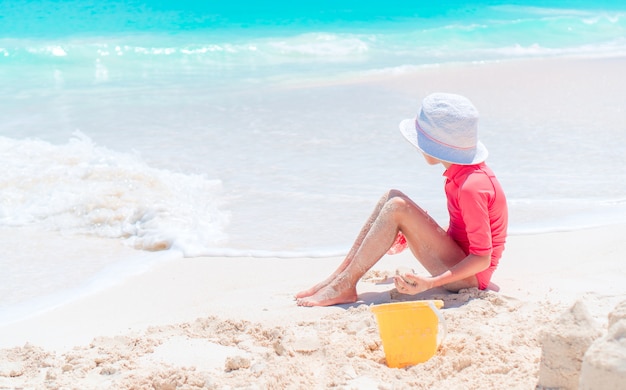 Menina adorável brincando com brinquedos de praia durante as férias tropicais