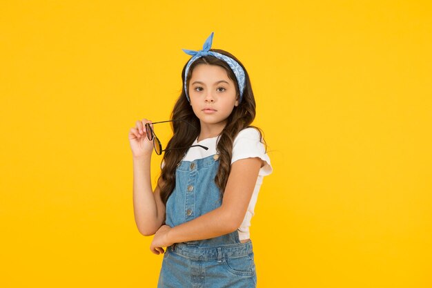 Menina adorável cabelo longo encaracolado segura óculos de sol conceito de moda de verão