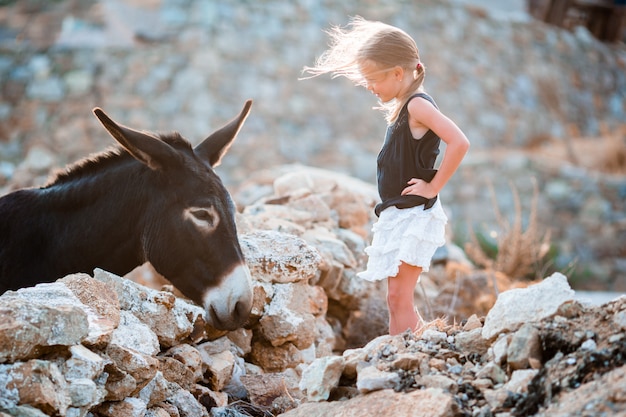 Menina adorável com burro em Mykonos