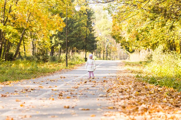 Menina adorável com folhas de outono no parque de beleza