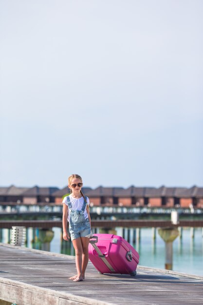 Menina adorável com grande bagagem durante as férias de verão