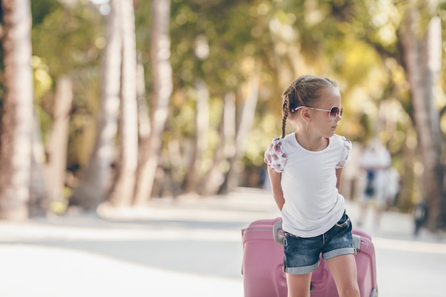 Menina adorável com grande bagagem durante as férias de verão