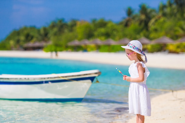 Menina adorável com pirulito na praia tropical