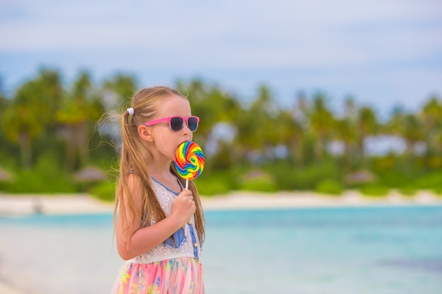 Menina adorável com pirulito na praia tropical