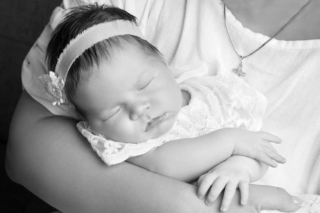 Menina adorável dormindo nas mãos da mãe Imagem aproximada Mãe feliz e seu bebê recém-nascido sorridente