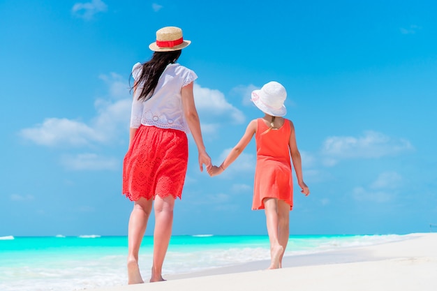 Menina adorável e jovem mãe na praia tropical