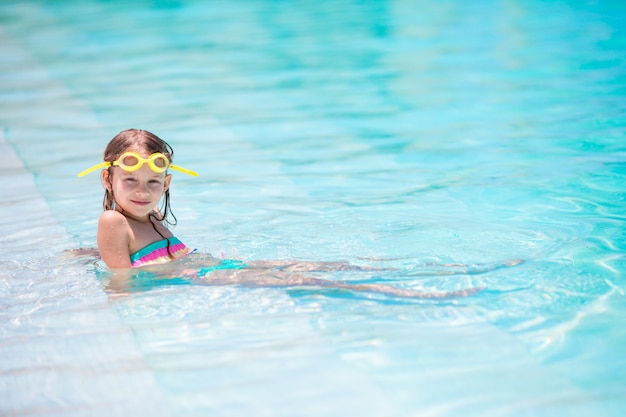 Menina adorável feliz na piscina ao ar livre