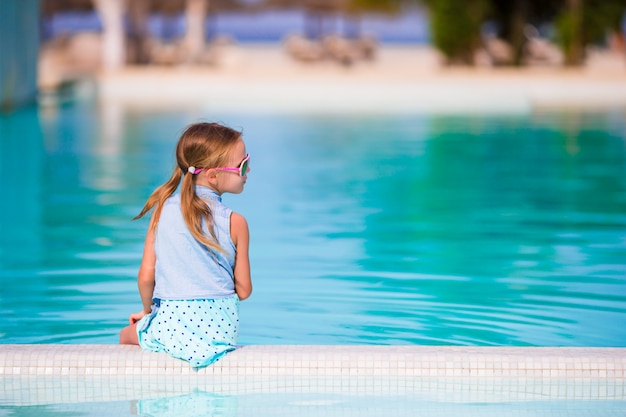 Menina adorável feliz na piscina ao ar livre