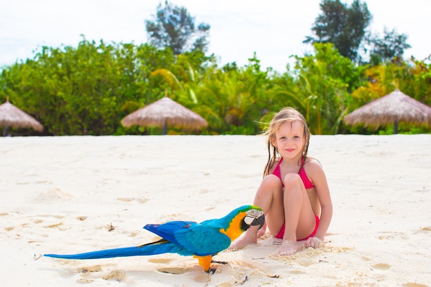 Menina adorável na praia com papagaio colorido