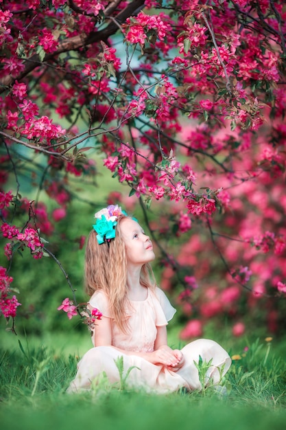 Menina adorável no belo jardim de maçã florescendo ao ar livre