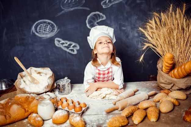 Menina adorável no chapéu de chef fazendo massa