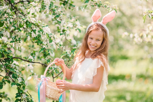 Menina adorável no jardim de maçã florescendo no lindo dia de primavera