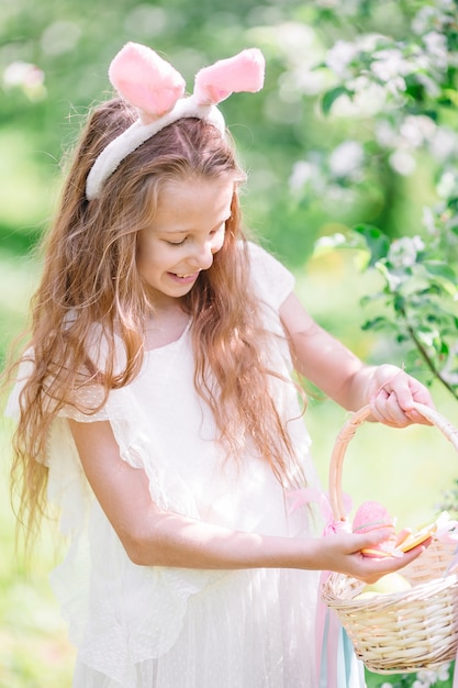 Menina adorável no jardim de maçã florescendo no lindo dia de primavera