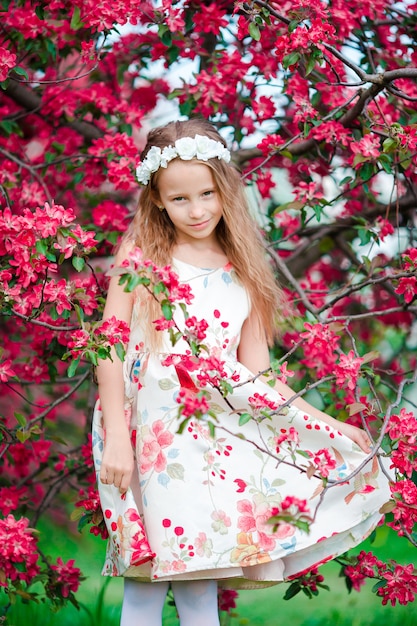 Menina adorável no jardim de macieira florescendo na primavera