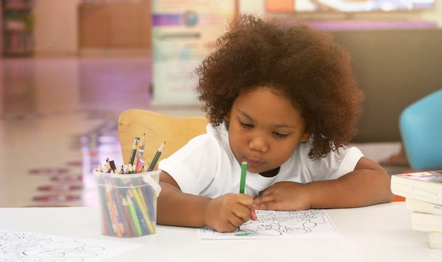 Foto menina africana pintando e desenhando com felicidade.