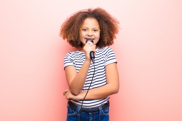 Menina afro-americana contra parede plana com microfone