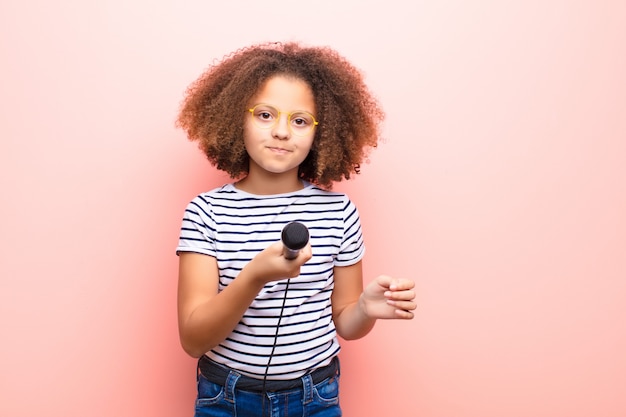 Menina afro-americana contra parede plana com microfone