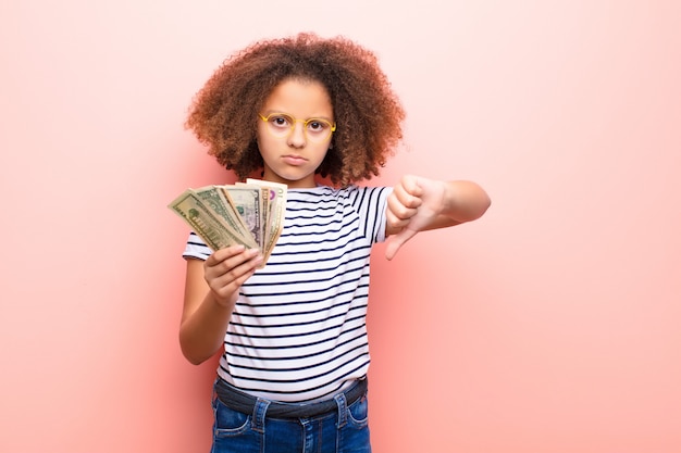 Menina afro-americana contra parede plana com notas de dólar