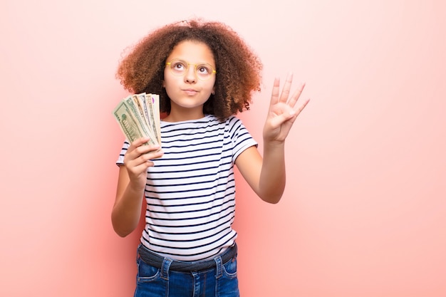 Menina afro-americana contra parede plana com notas de dólar