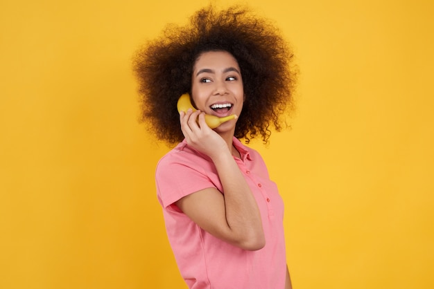 Menina afro-americano que levanta com a banana isolada.