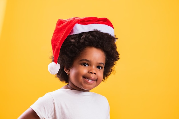 Menina afro com chapéu de papai noel, sorrindo para a câmera