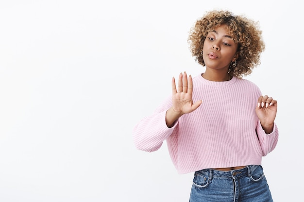 Menina agindo como se não estivesse interessada em assoar as unhas depois de visitar o salão, unhas morrendo parecendo despreocupada e relaxada, encantada com um bom esmalte de pé sobre uma parede branca