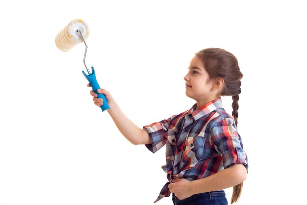 Menina agradável com longa trança castanha na camisa xadrez vermelha e jeans azul segurando rolo branco