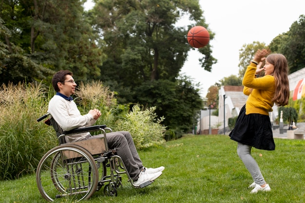 Menina ajudando homem deficiente a jogar basquete