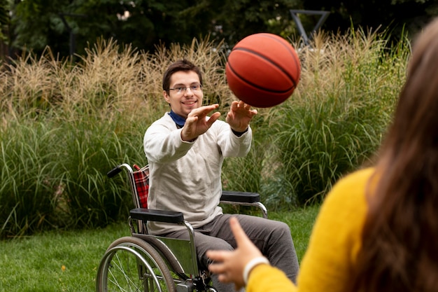 Foto menina ajudando homem deficiente a jogar basquete