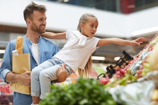 Foto menina alcançando frutas no mercado