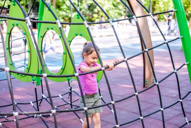 Menina alegre brinca de férias no parque no playground A criança se diverte na rua nas férias A criança pratica esportes em simuladores