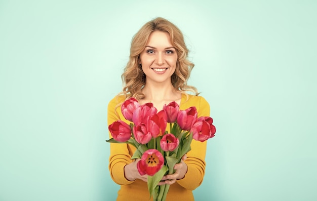 Menina alegre com flores de tulipa de primavera em fundo azul