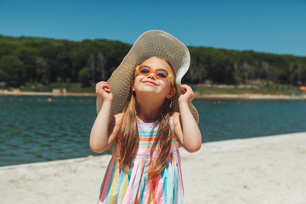 Menina alegre com síndrome de down em um chapéu de verão na praia