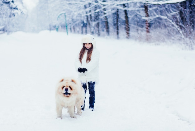 Menina alegre com um cachorro chow chow em winter park.