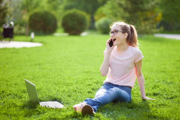 Menina alegre de óculos falando ao telefone no parque