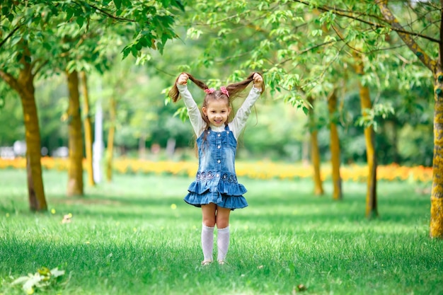 Menina alegre e feliz com os braços estendidos verão em um vestido azul ao ar livre em um parque smil