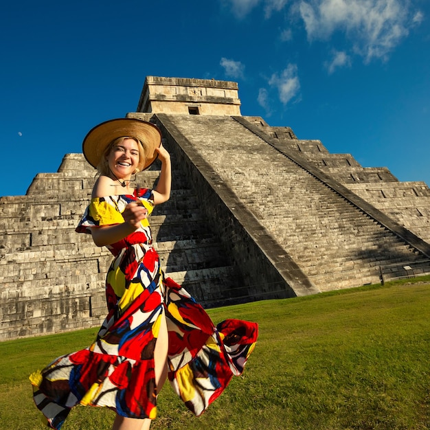 Menina alegre em um chapéu e vestido colorido ao redor da pirâmide em Chichen Itza Yucatan México